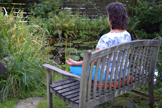 Frau beim Yoga auf Gartenbank