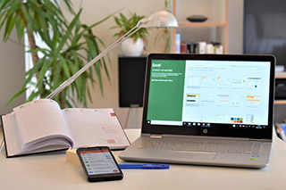 Laptop, Smartphone und Kalender auf einem Tisch